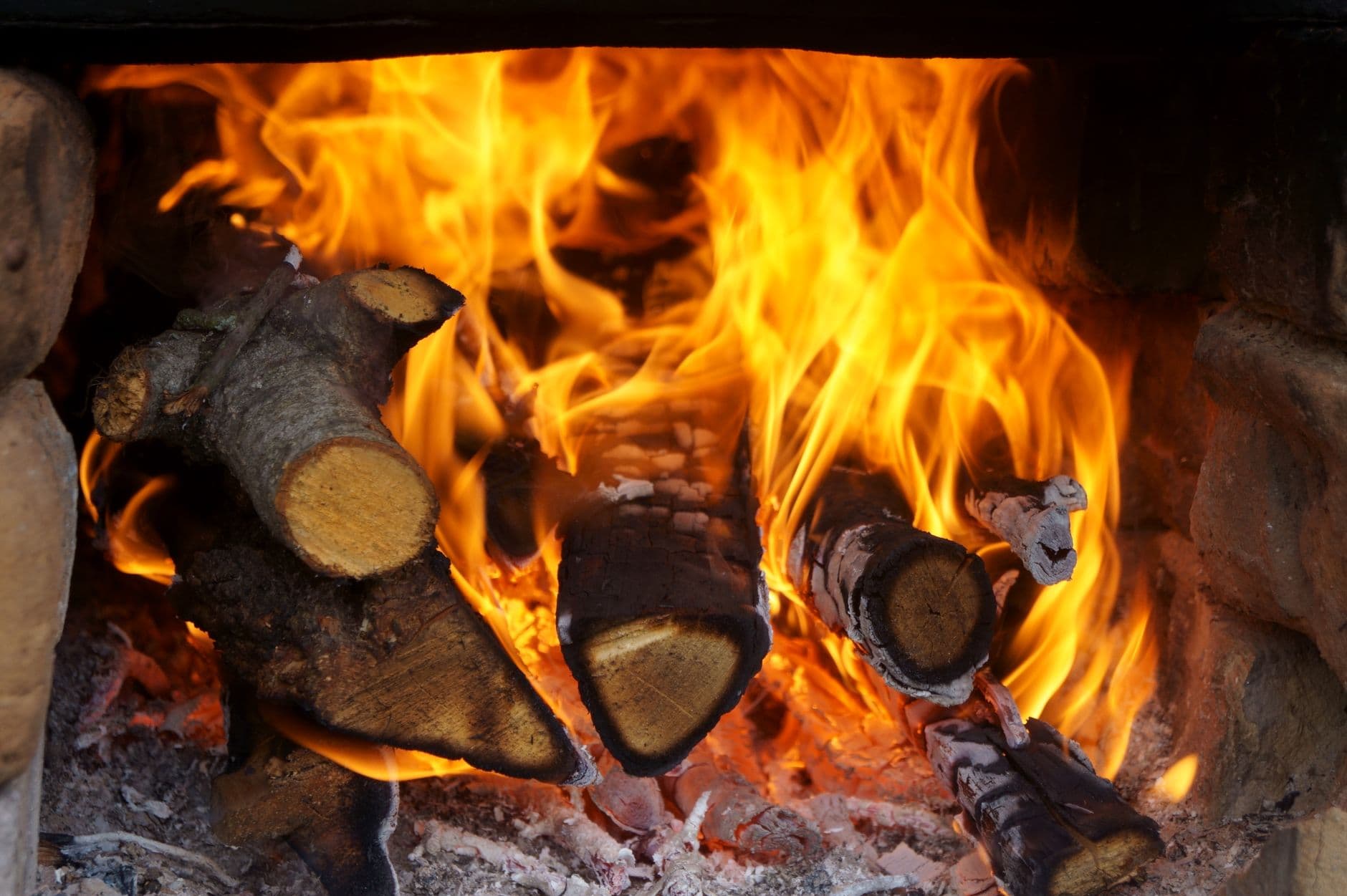 A detailed close-up of firewood burning intensely in a cozy indoor fireplace.