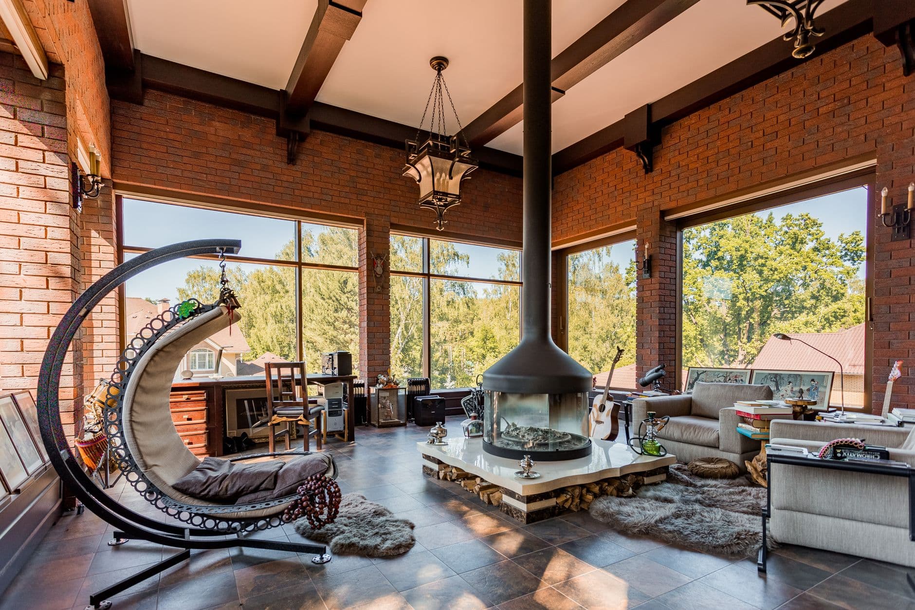 Elegant, sunlit interior with modern design, featuring a central fireplace and cozy swing chair.